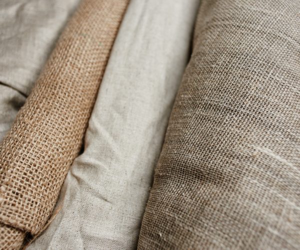 Natural fabrics from organic colors of flax and cotton in rolls, homespun textile handmade. Burlap and canvas for eco, rustic, boho, hygge decor